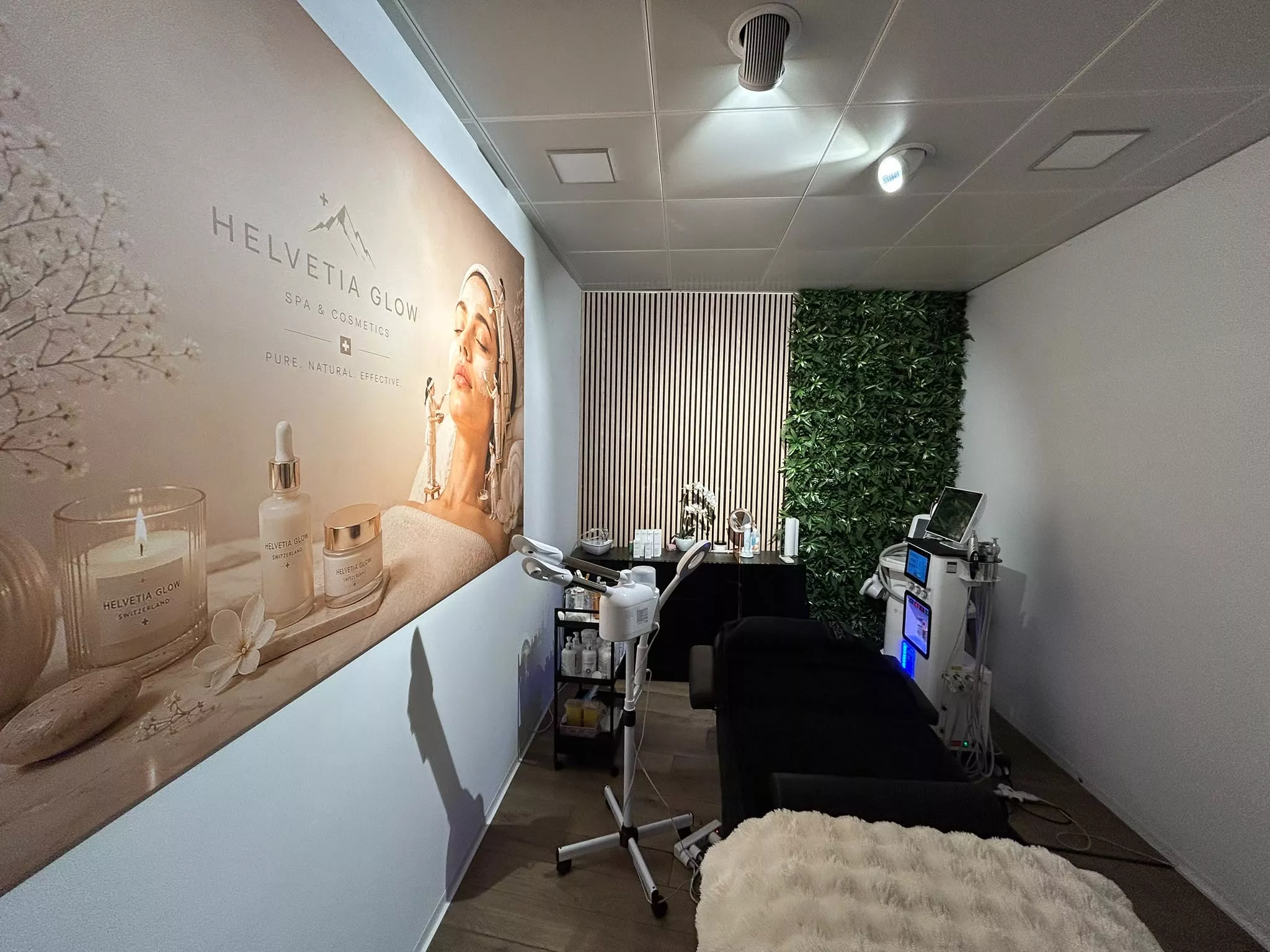 Helvetia Glow Behandlungsraum in Basel – Wandbild, grüne Pflanzenwand und moderne Kosmetikgeräte