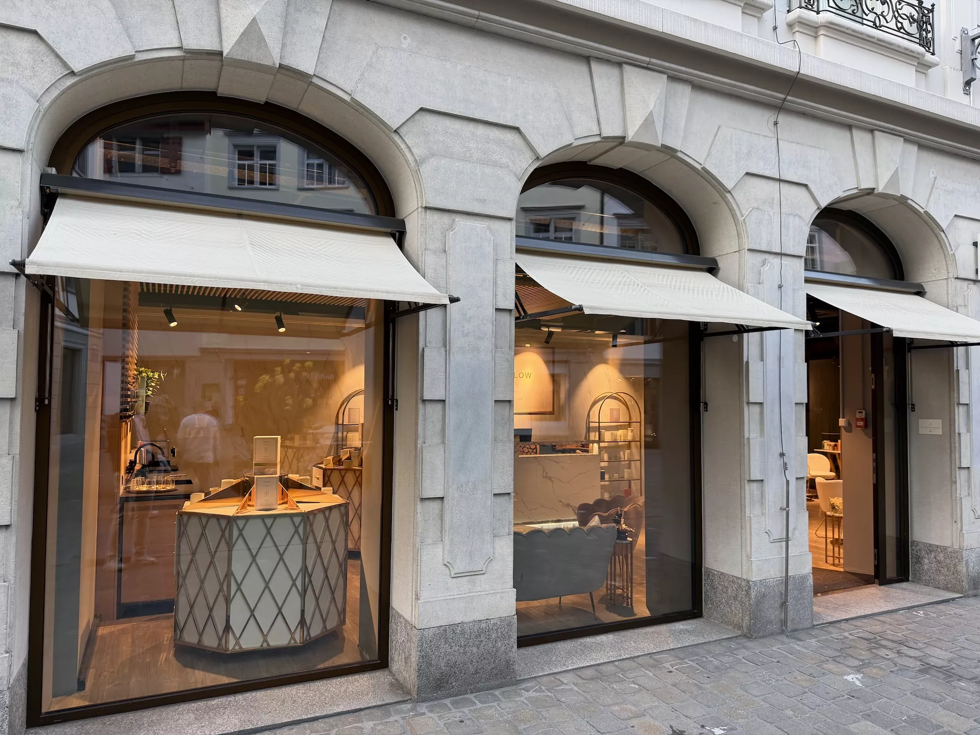 Aussenansicht der Helvetia Glow Boutique mit Arkadenfenstern und Markisen
